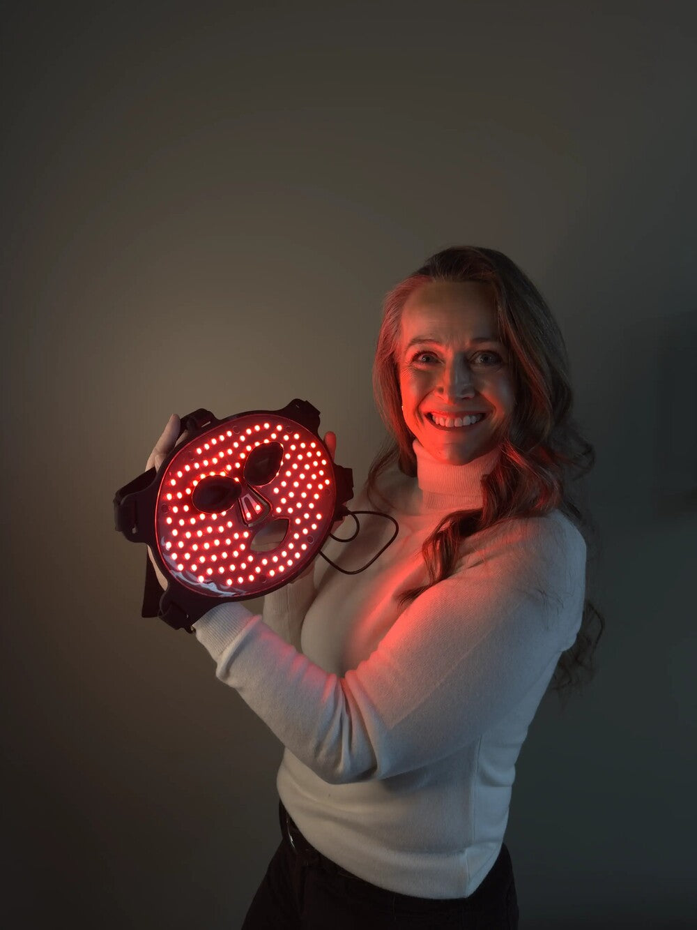 Kvinne holder RedHeal Quantum LED-maske med rødt lys